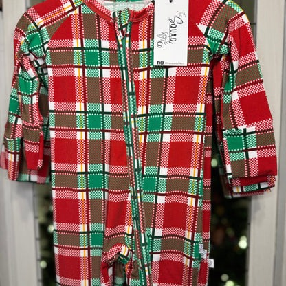 Plaid you're here convertible romper close up hanging in front of a Christmas tree.